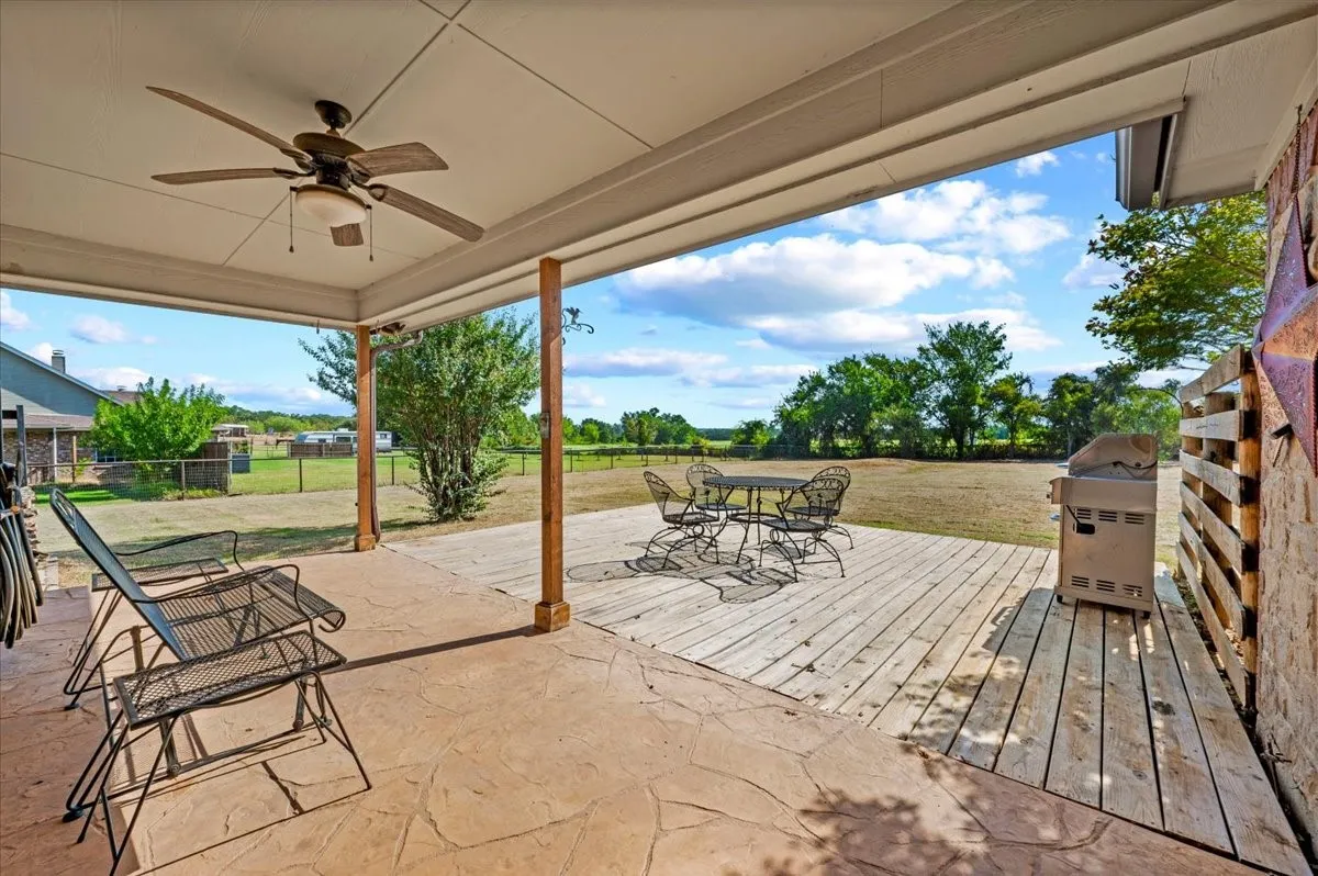 Covered patio featuring an outdoor ceiling fan, stamped concrete, and a wood-plank deck