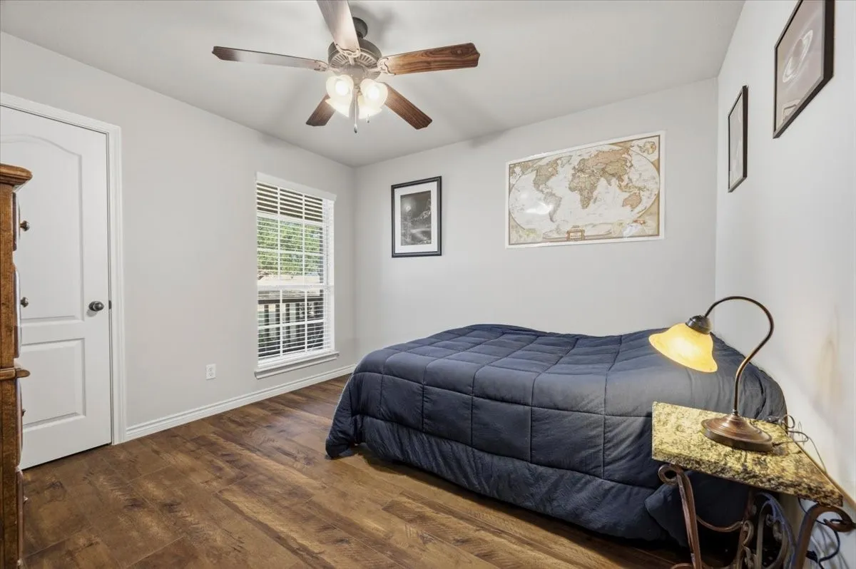 Wood-finish flooring, ceiling fan with integrated lighting, white trim, and window with blinds