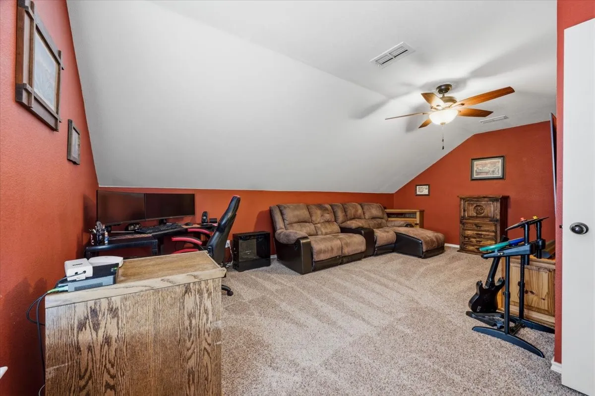 Sloped ceiling architectural detail, built-in shelving, sconce lighting, and carpet flooring