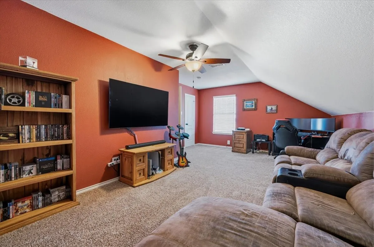 Sloped ceilings, textured walls, ceiling fan, and carpet flooring