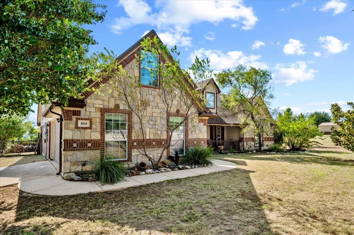 Stone and brick exterior with dormer windows, featuring an attached garage and a covered front porch