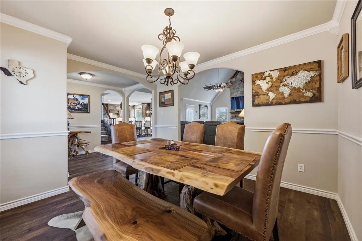 Elegant dining room showcasing a live-edge wood table with matching bench seating, upholstered dining chairs with nailhead trim, and a brass chandelier with multiple light sources