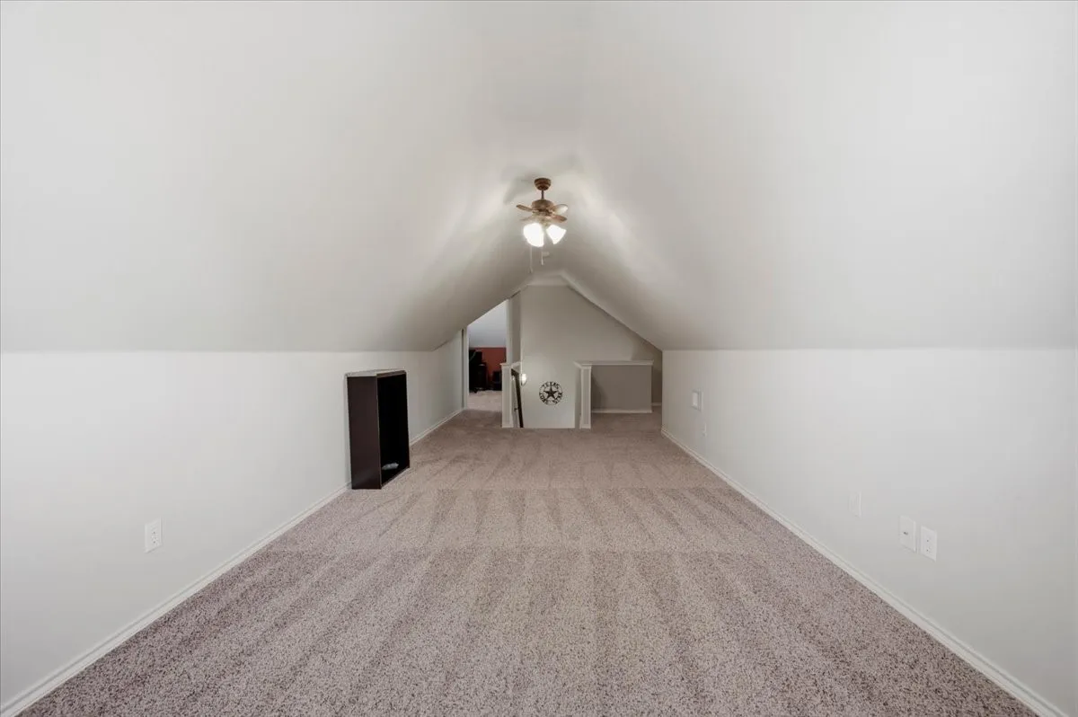 Sloped ceilings, textured wall finish, and a ceiling fan with integrated lighting