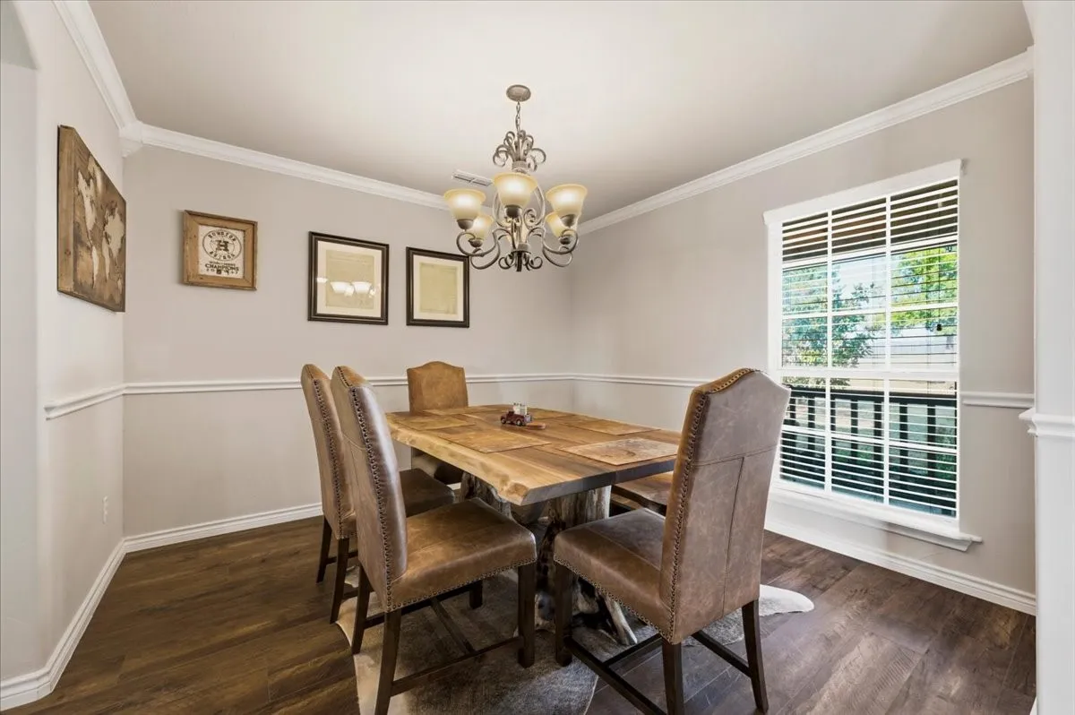 Wood-finish flooring with white baseboards, crown molding, and chair rail detailing