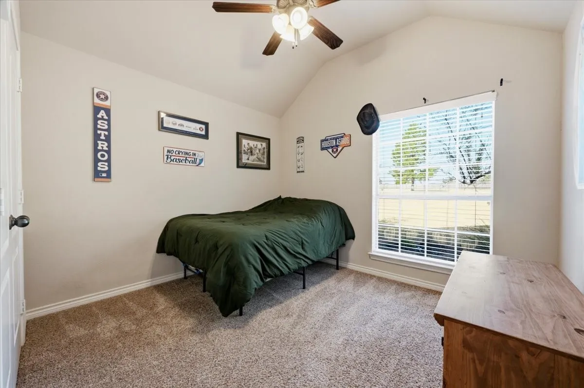 Vaulted ceiling with a ceiling fan, carpet flooring, and a window with blinds