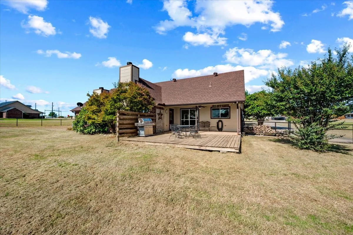 Expansive backyard featuring a wood deck, perimeter fencing, and mature trees
