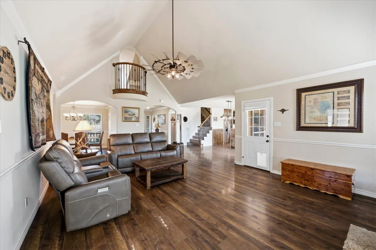 Spacious great room showcasing vaulted ceilings with skylights, dark wood-finish flooring throughout, and a pendant light fixture