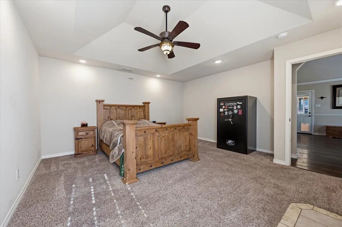 Tray ceiling with recessed lighting, ceiling fan with light fixture, neutral wall color, and carpet flooring