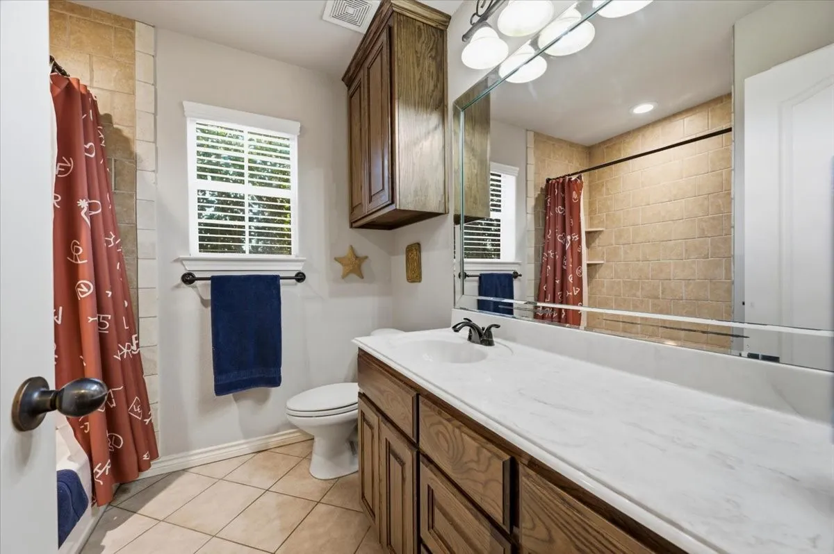 Spa-inspired primary bathroom featuring dual vanity with white quartz countertop, wood-finish cabinetry, and chrome fixtures