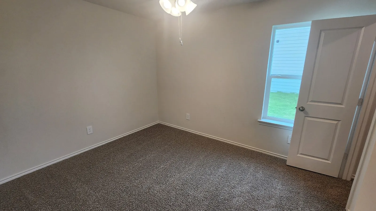 Neutral wall finishes, textured carpeting, a window, and a ceiling fan with integrated lighting