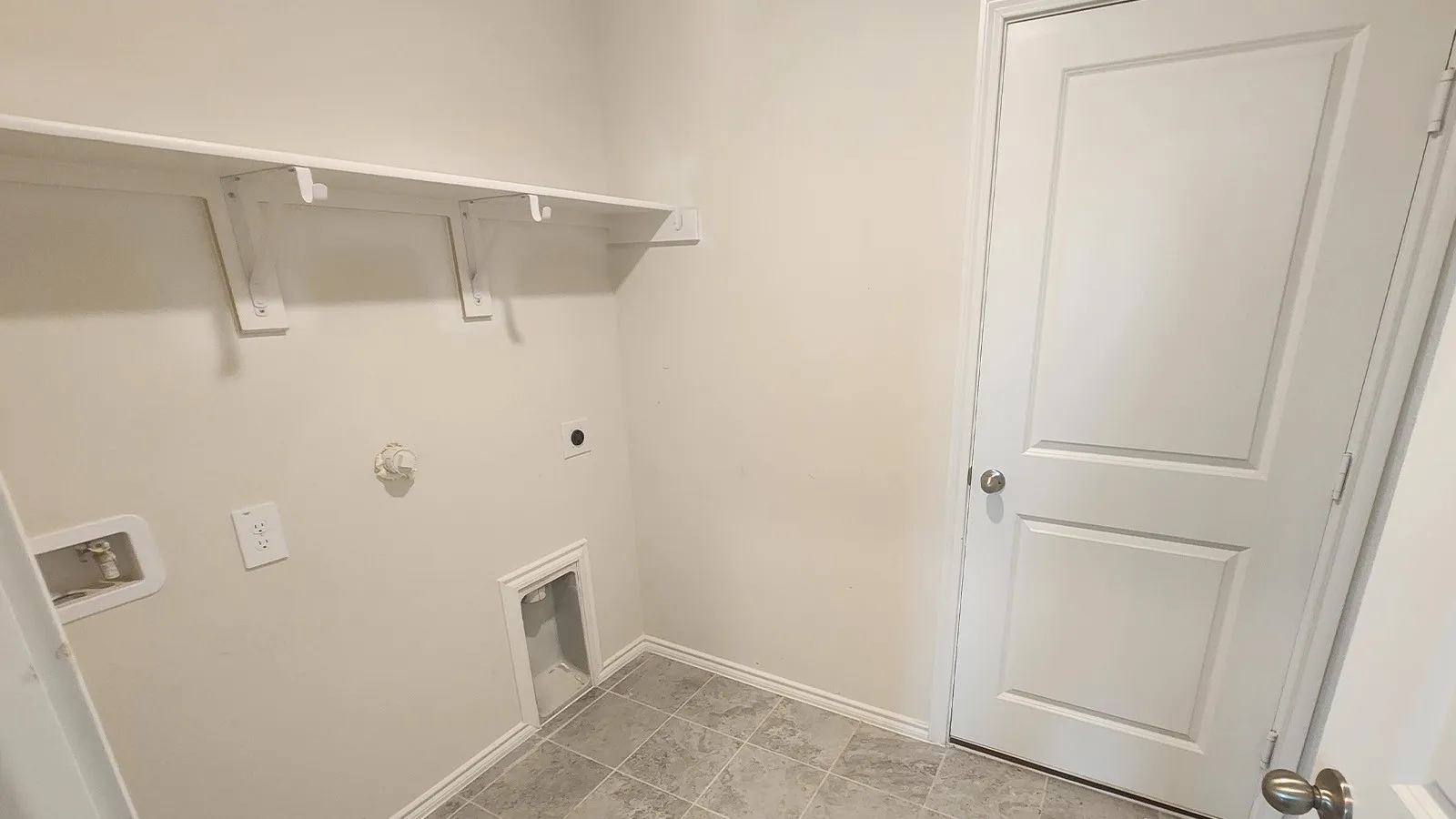 Integrated shelving system, white interior door, tiled flooring, neutral wall tones, and utility hookups