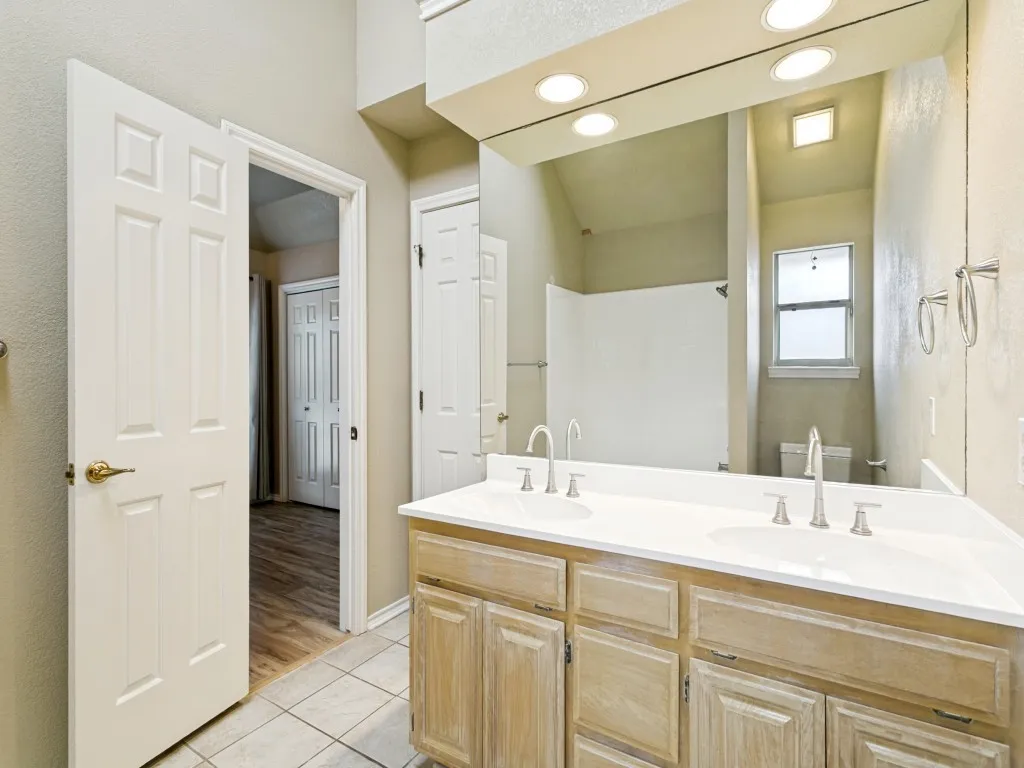 Dual vanity with integrated sinks, brushed nickel faucets, and a large mirror with recessed lighting
