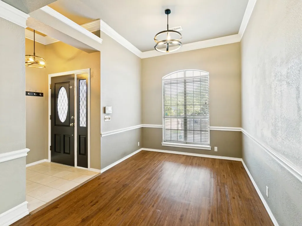 Wood-finish flooring, crown molding, chair rail molding, arched window with blinds, and a contemporary ceiling fixture