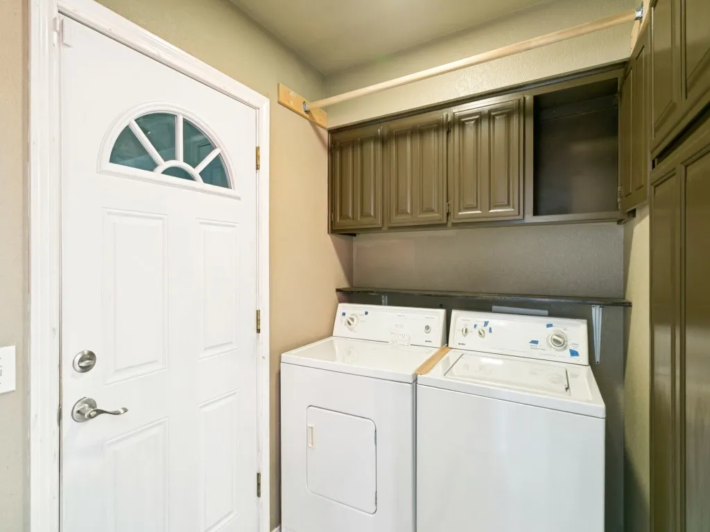 Laundry area featuring built-in cabinetry, a dark countertop, and a white paneled door with an arched window