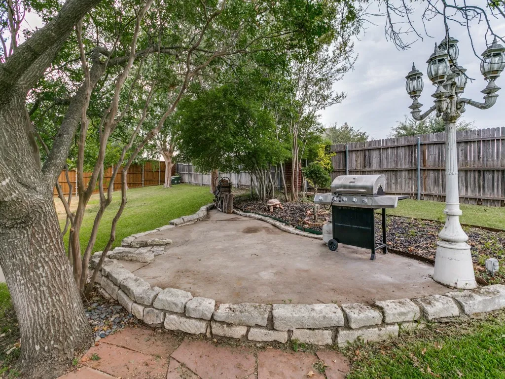 Paved patio area with a stone retaining wall, bordering a landscaped bed
