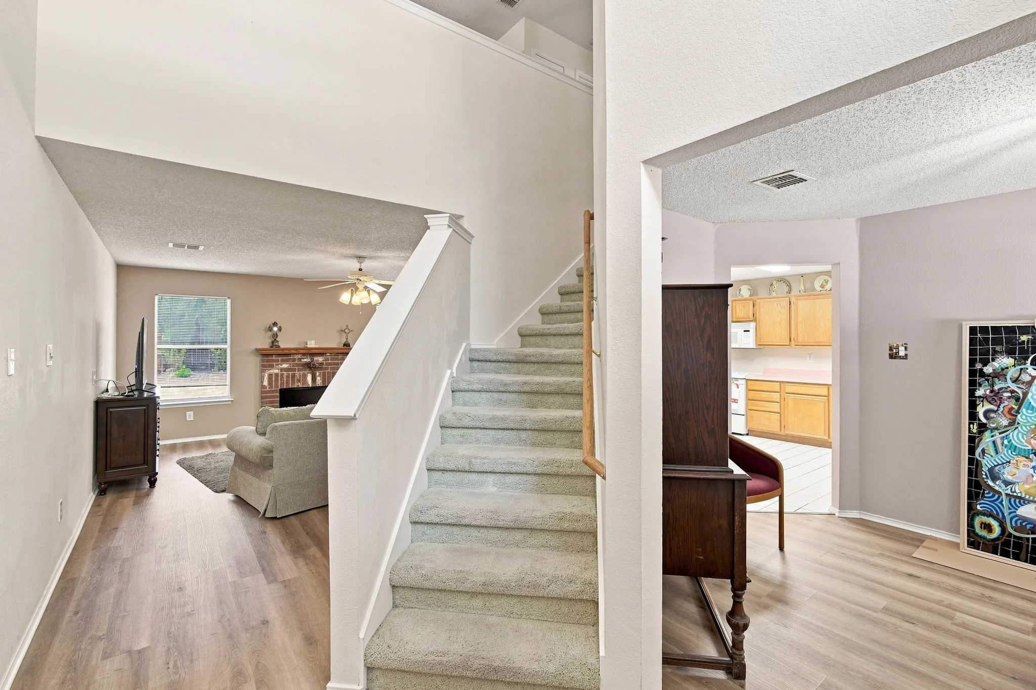 Carpeted staircase with white balustrade, wood-finish flooring, and a recessed ceiling