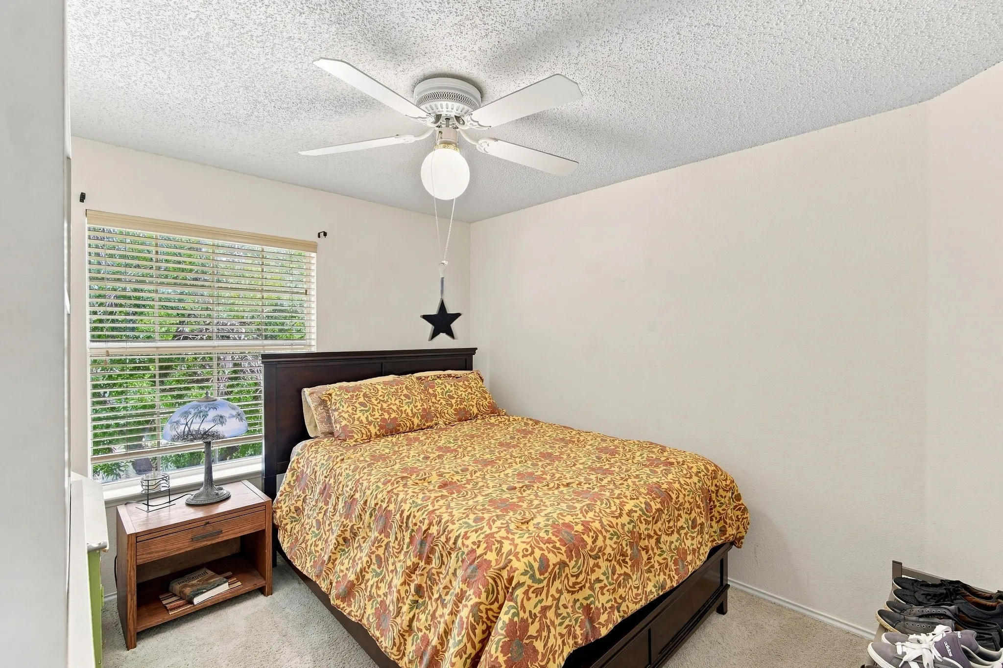 Carpeted bedroom with a window featuring blinds, a ceiling fan with integrated lighting, and neutral wall tones