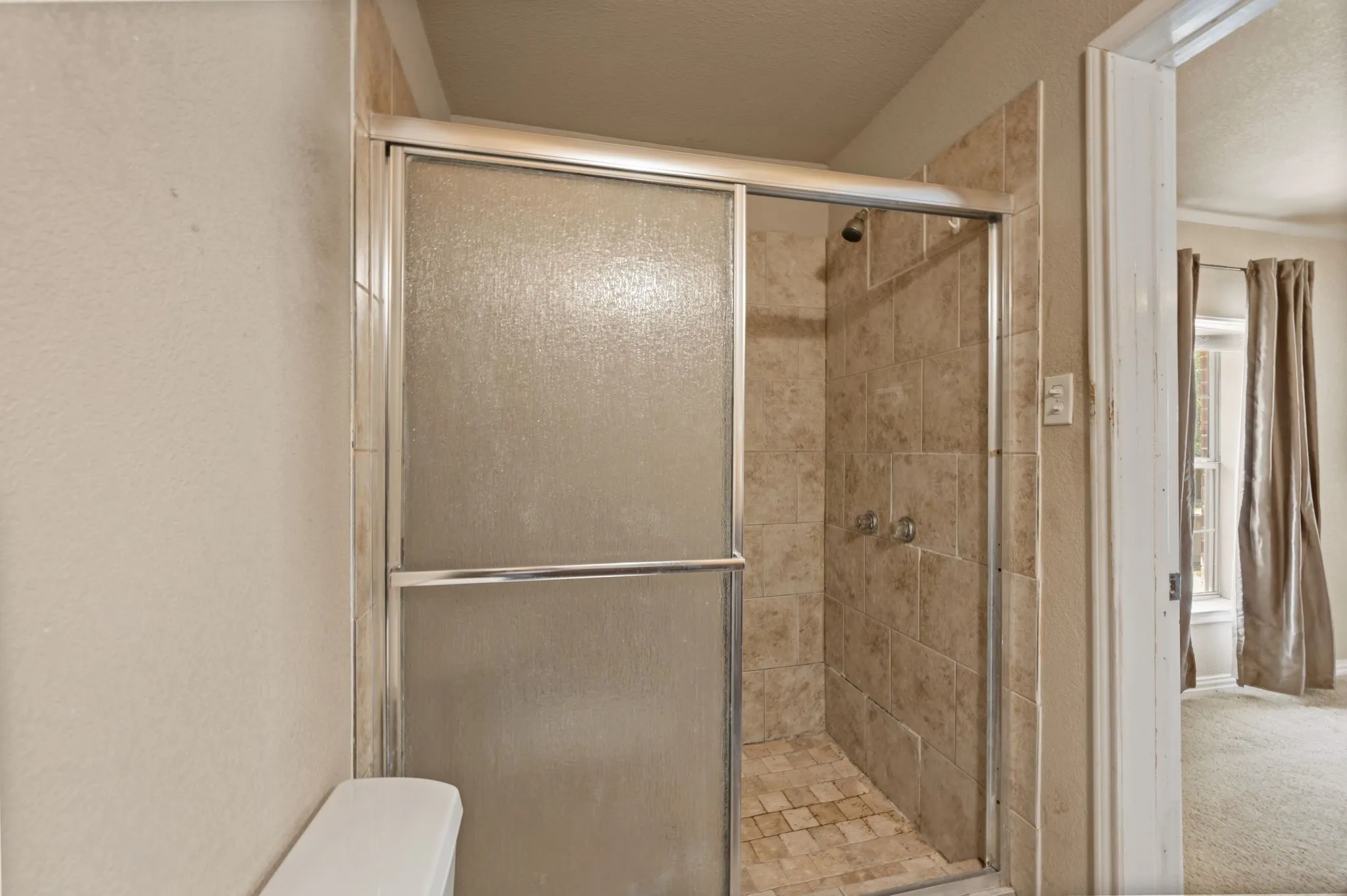 Shower enclosure with textured glass doors, tiled walls, and a tiled shower pan