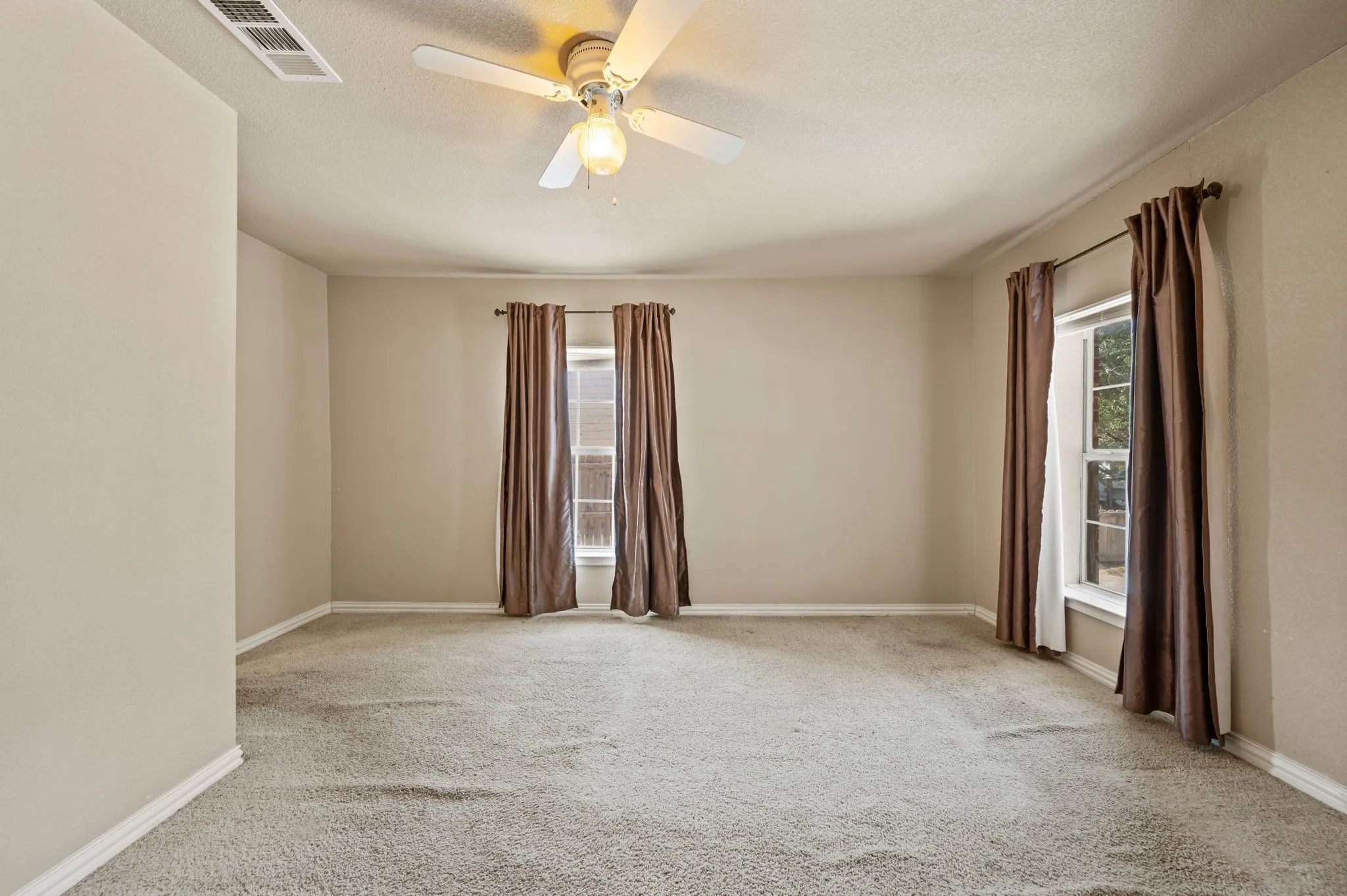 Wall-to-wall carpeting, multiple windows, window treatments, and a ceiling fan with integrated lighting