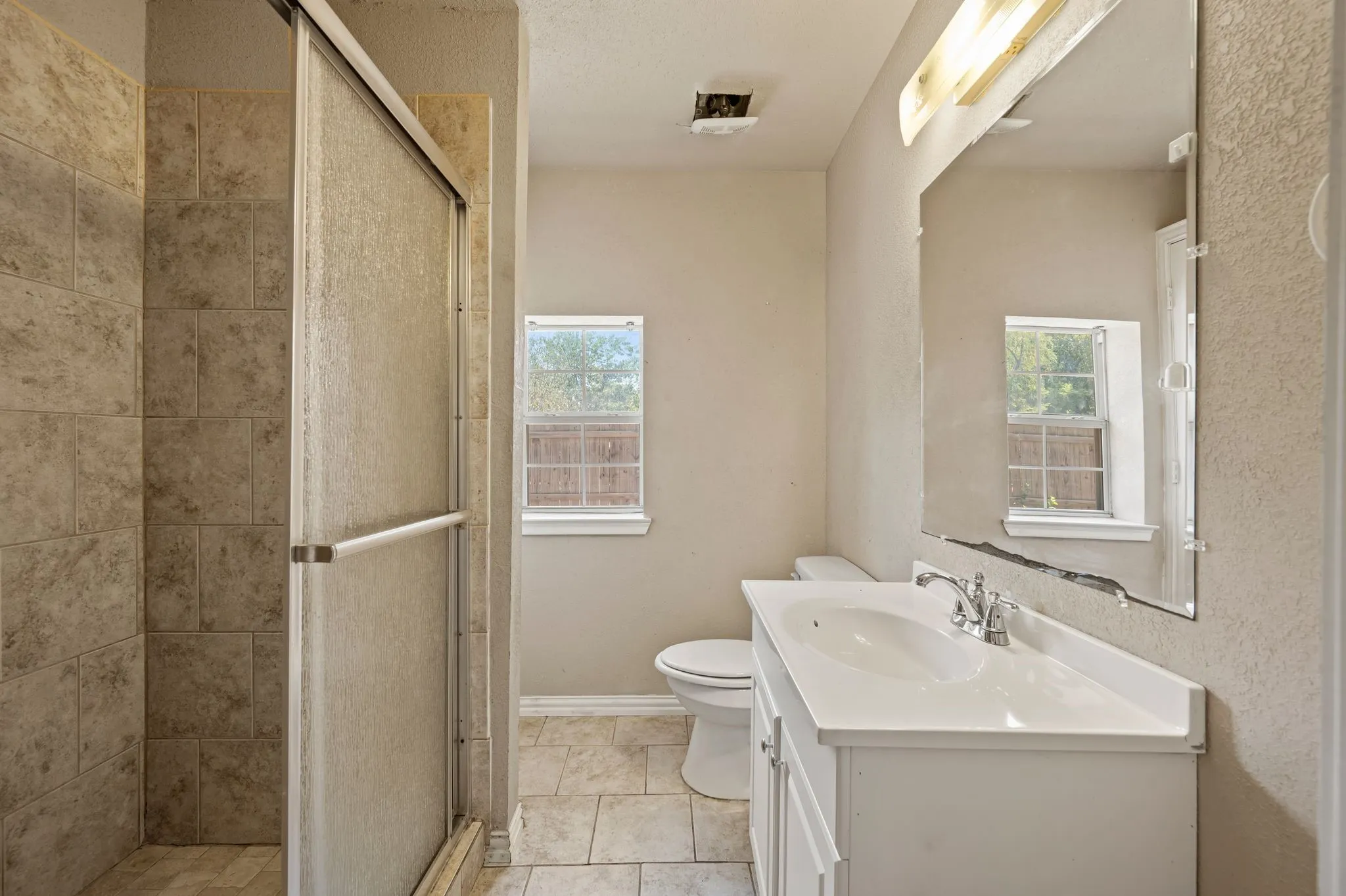 Vanity with integrated sink, chrome faucet, and expansive mirror