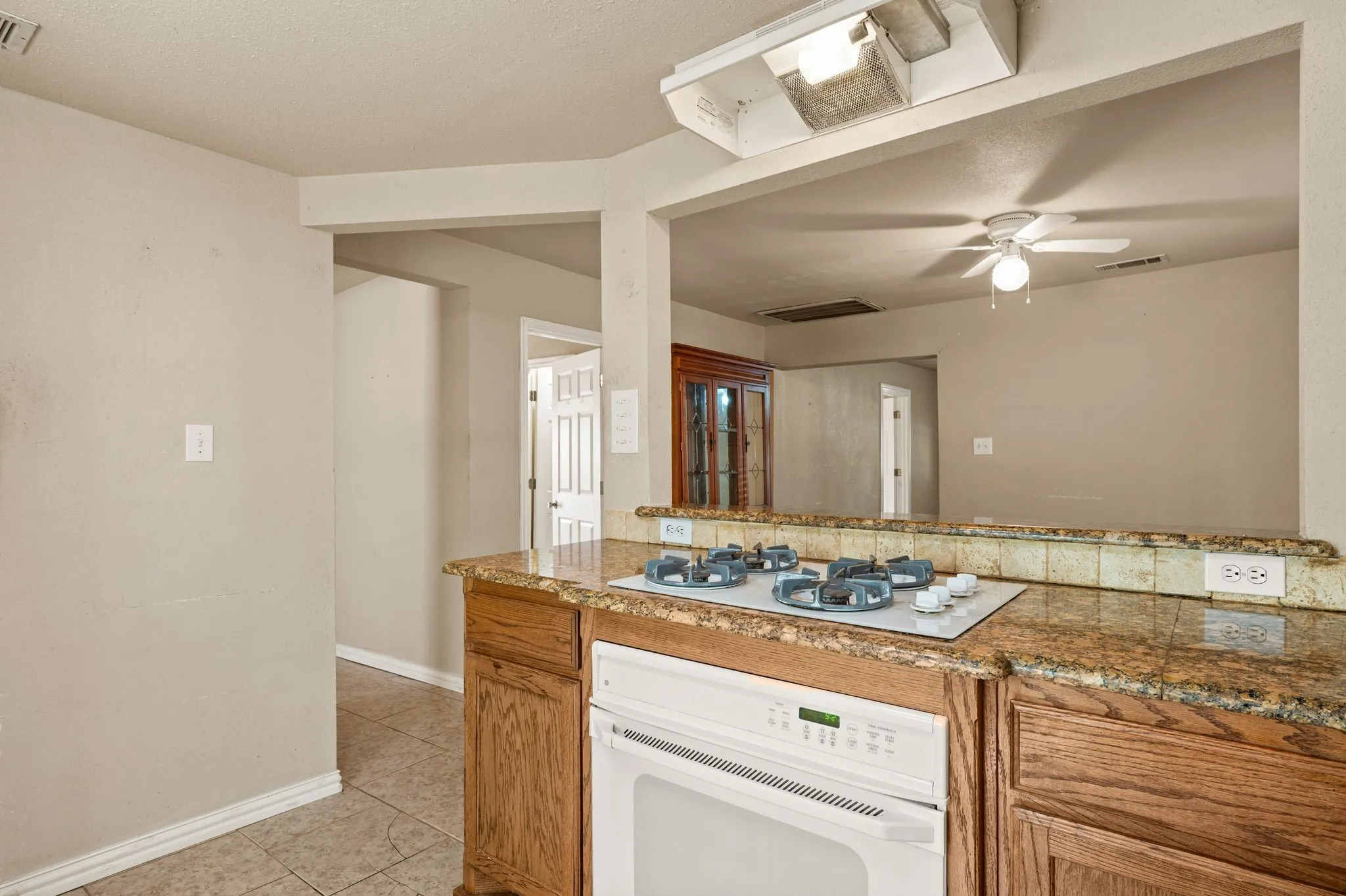 Kitchen featuring a built-in oven, integrated cooktop, wood cabinetry, granite-finish countertops, and a tiled backsplash