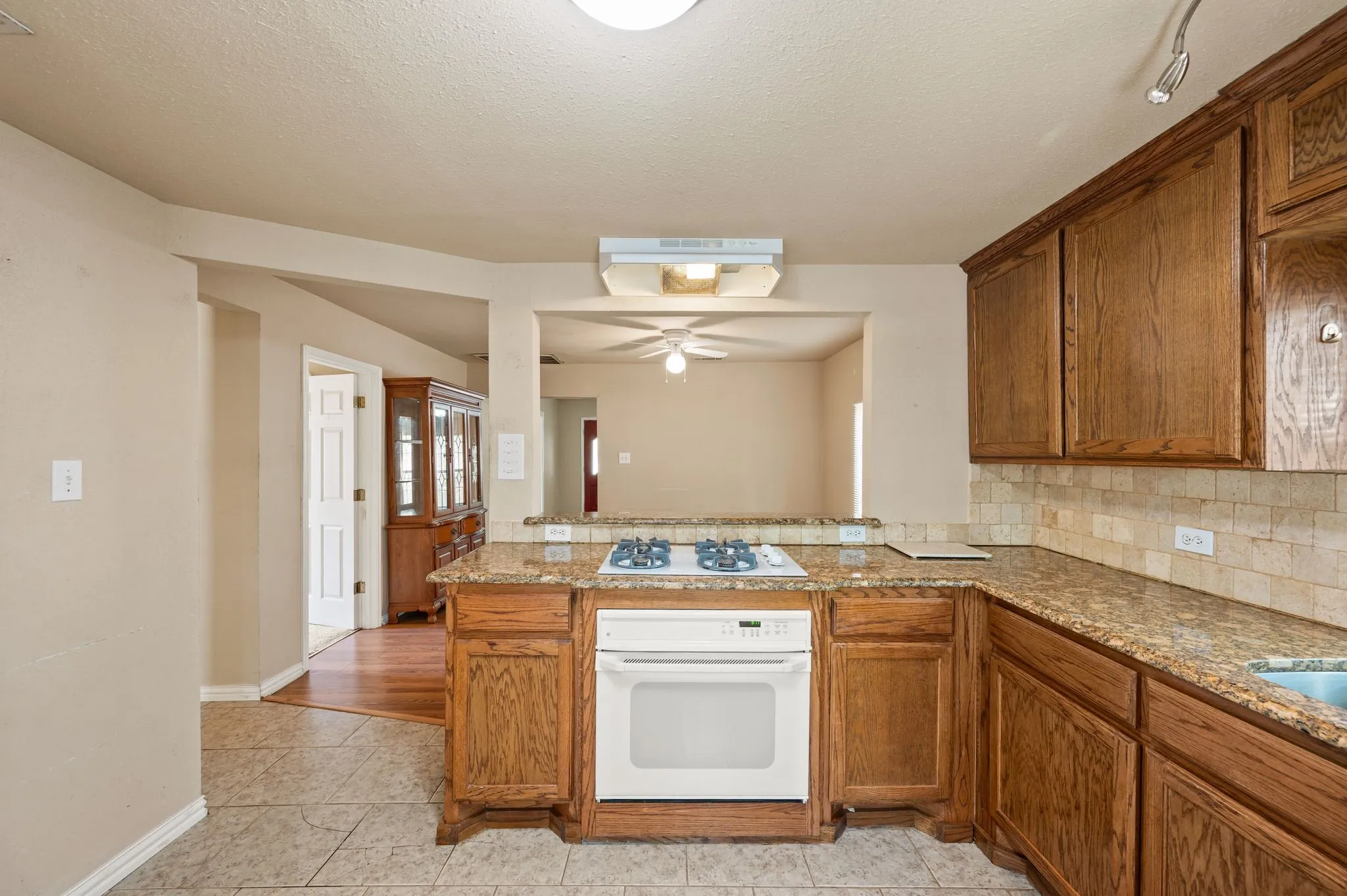 Kitchen featuring wood cabinetry, stone countertops, a tile backsplash, and a built-in oven with a gas cooktop