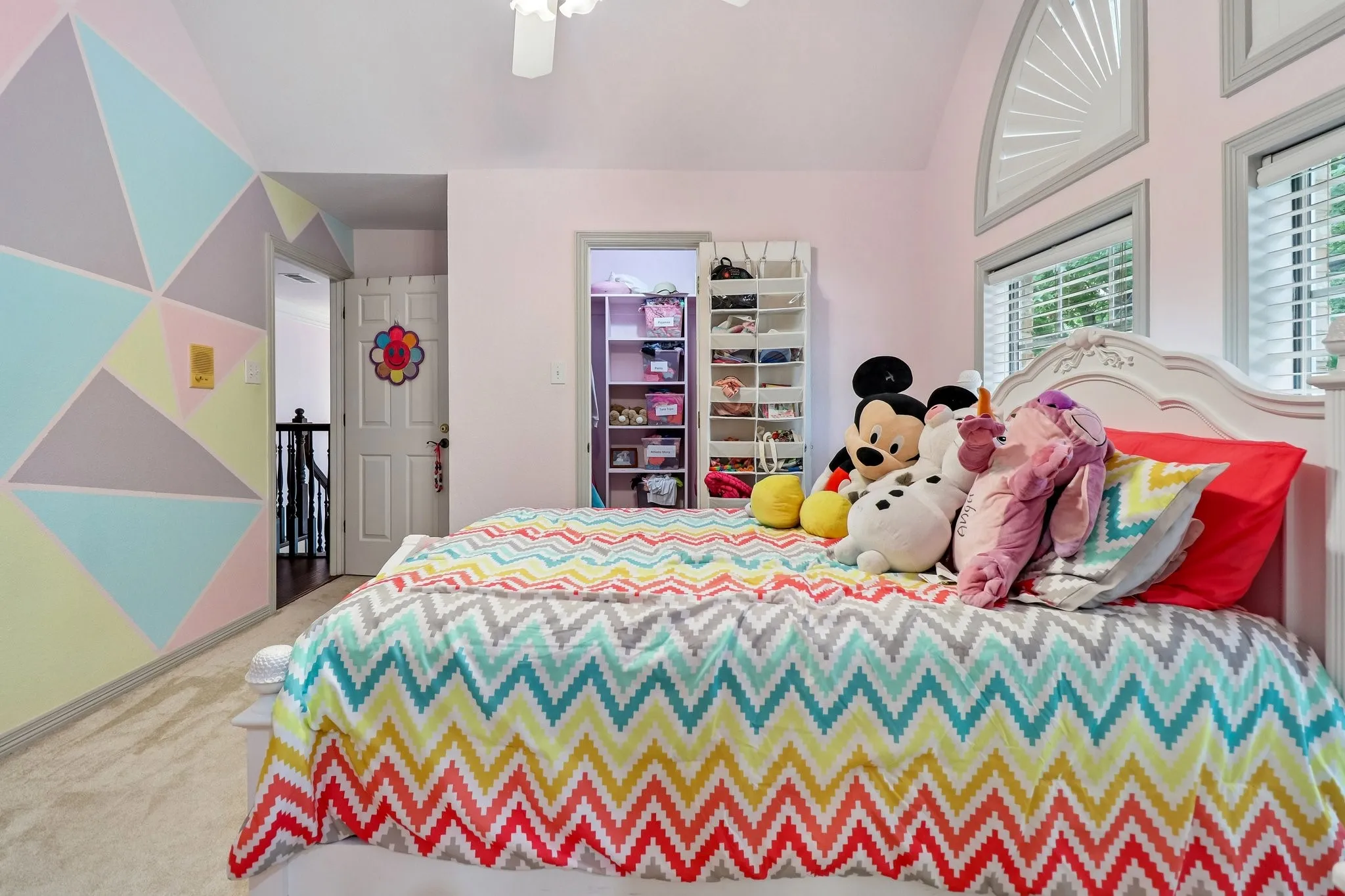 Vaulted ceiling with a ceiling fan, arched transom window, and a built-in closet organization system