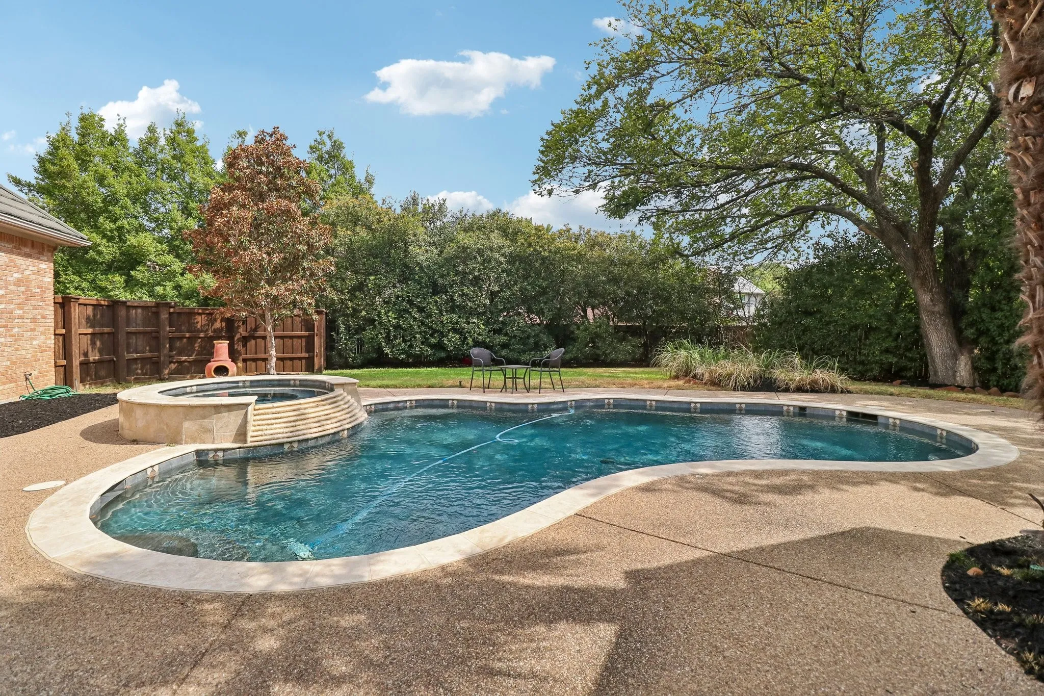 Freeform swimming pool with integrated spa and stone coping