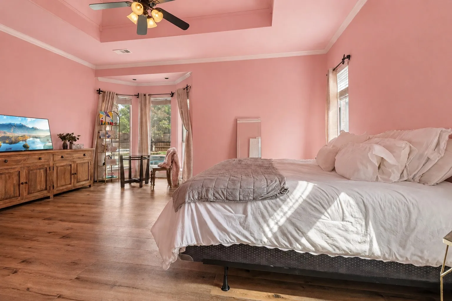 Coffer ceiling featuring a ceiling fan, wood-finish flooring, and bay window with natural light