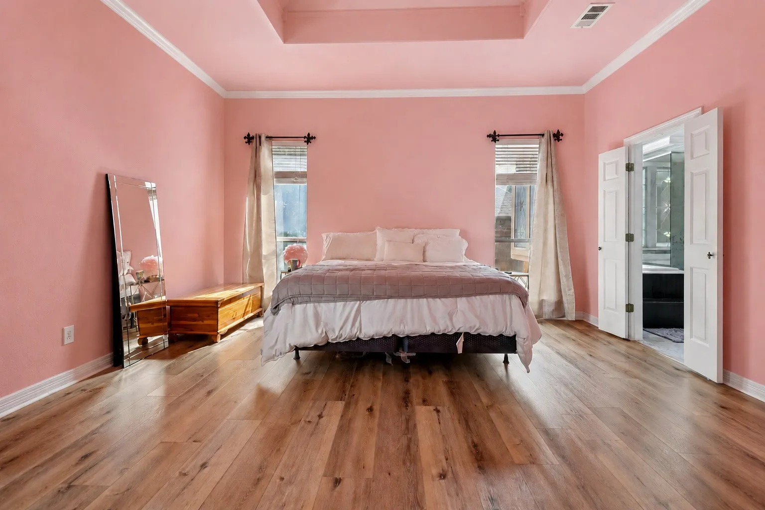 Wood-finish flooring, white crown molding, tray ceiling, and a double-door entry