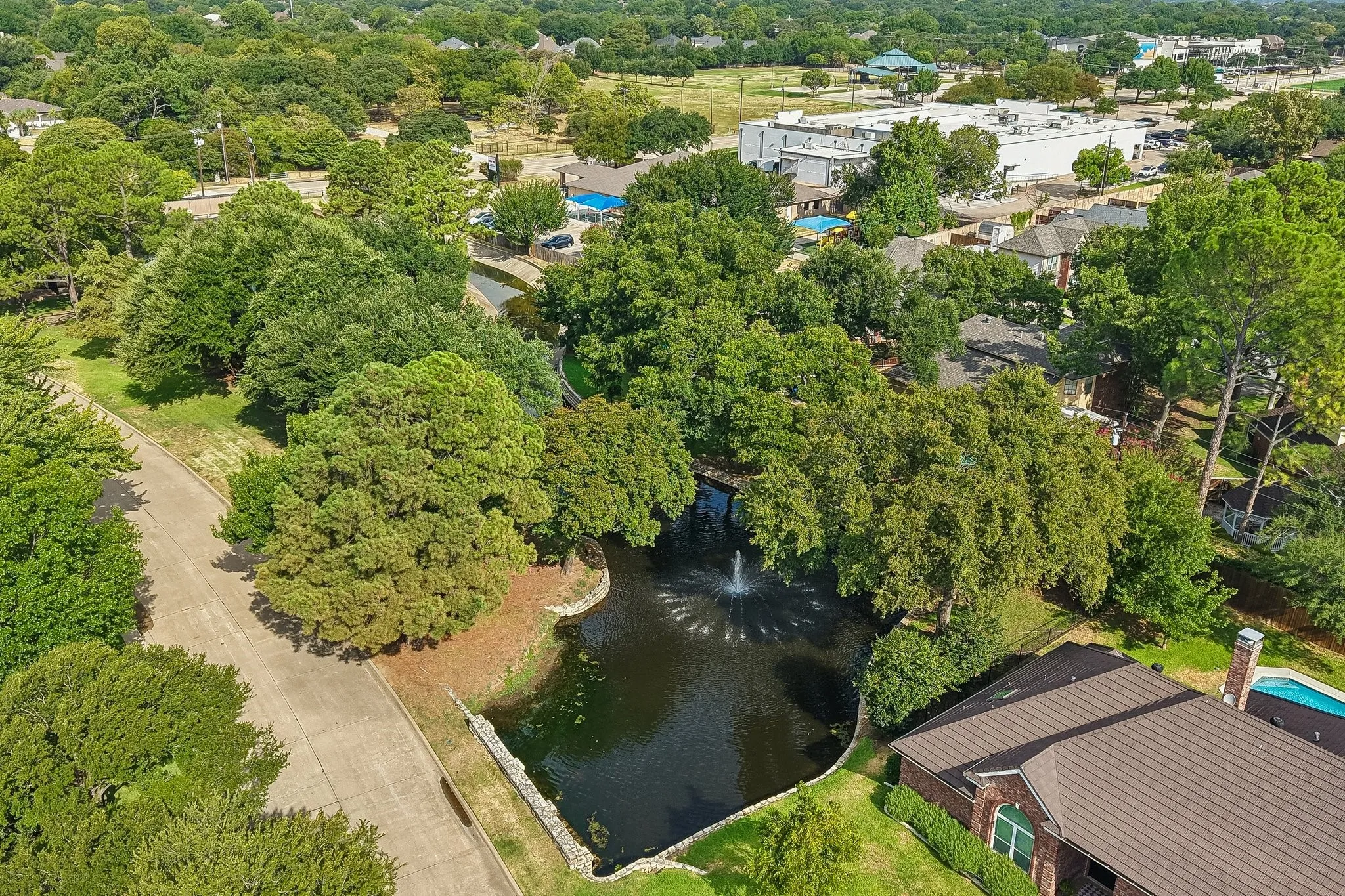 Aerial perspective showcasing a property adjacent to a pond with a fountain feature