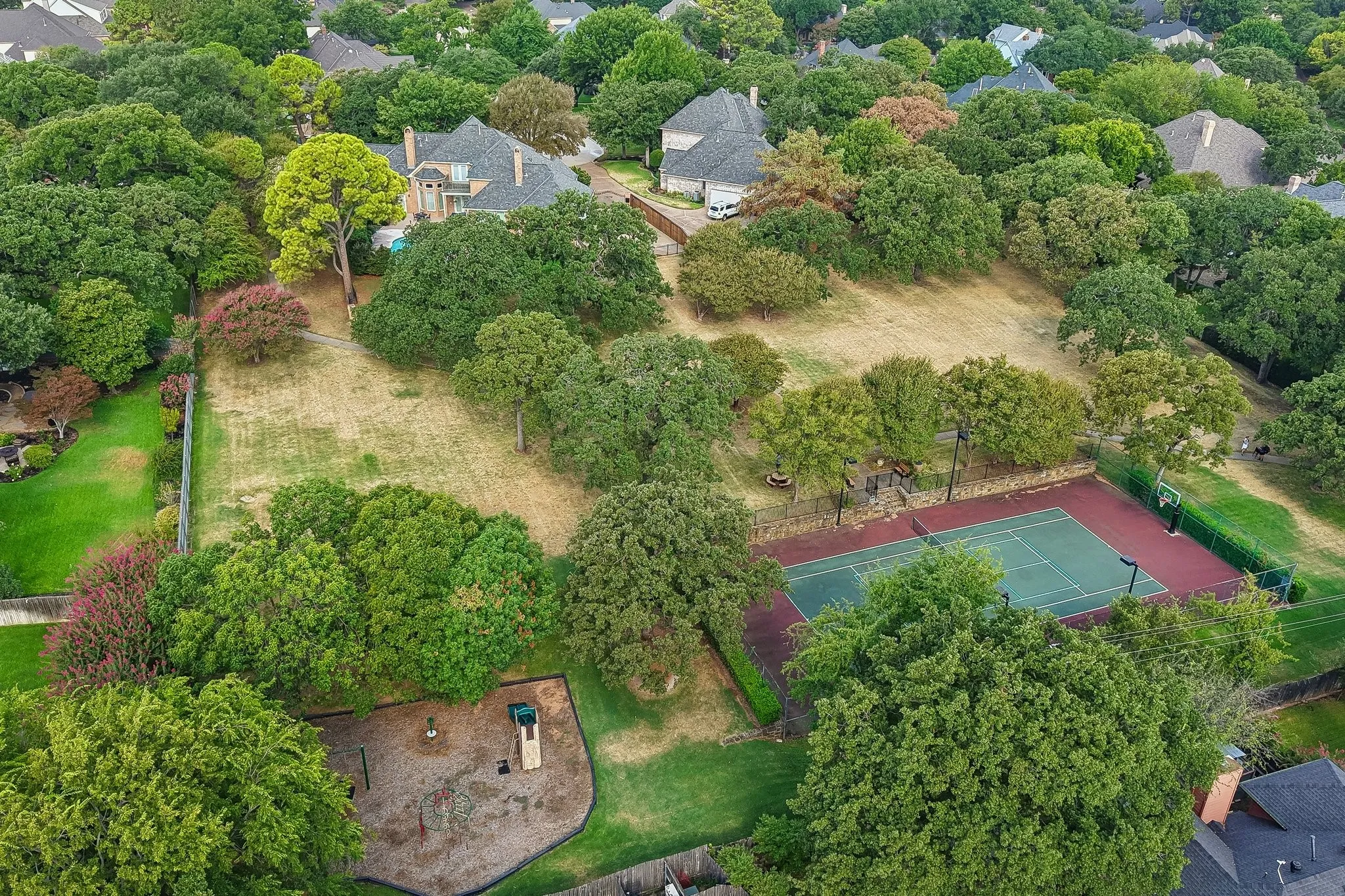 Expansive property featuring a private tennis court, playground area, and abundant mature trees