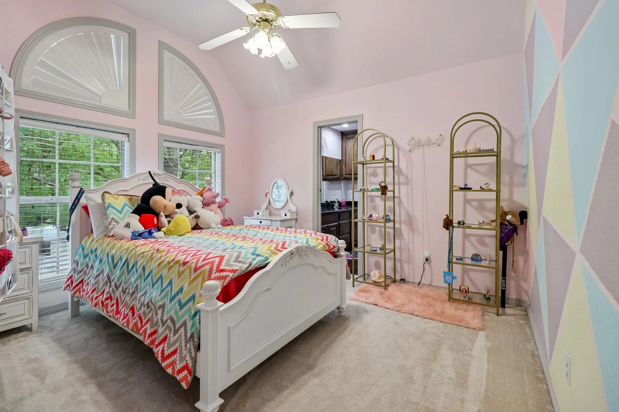 Vaulted ceiling with a ceiling fan, arched windows, and soft neutral carpeting