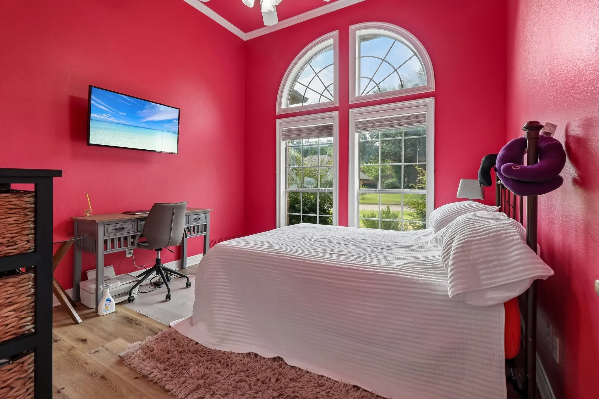 Vaulted ceiling with a ceiling fan, arched transom windows, wood-finish flooring, and bright wall finishes