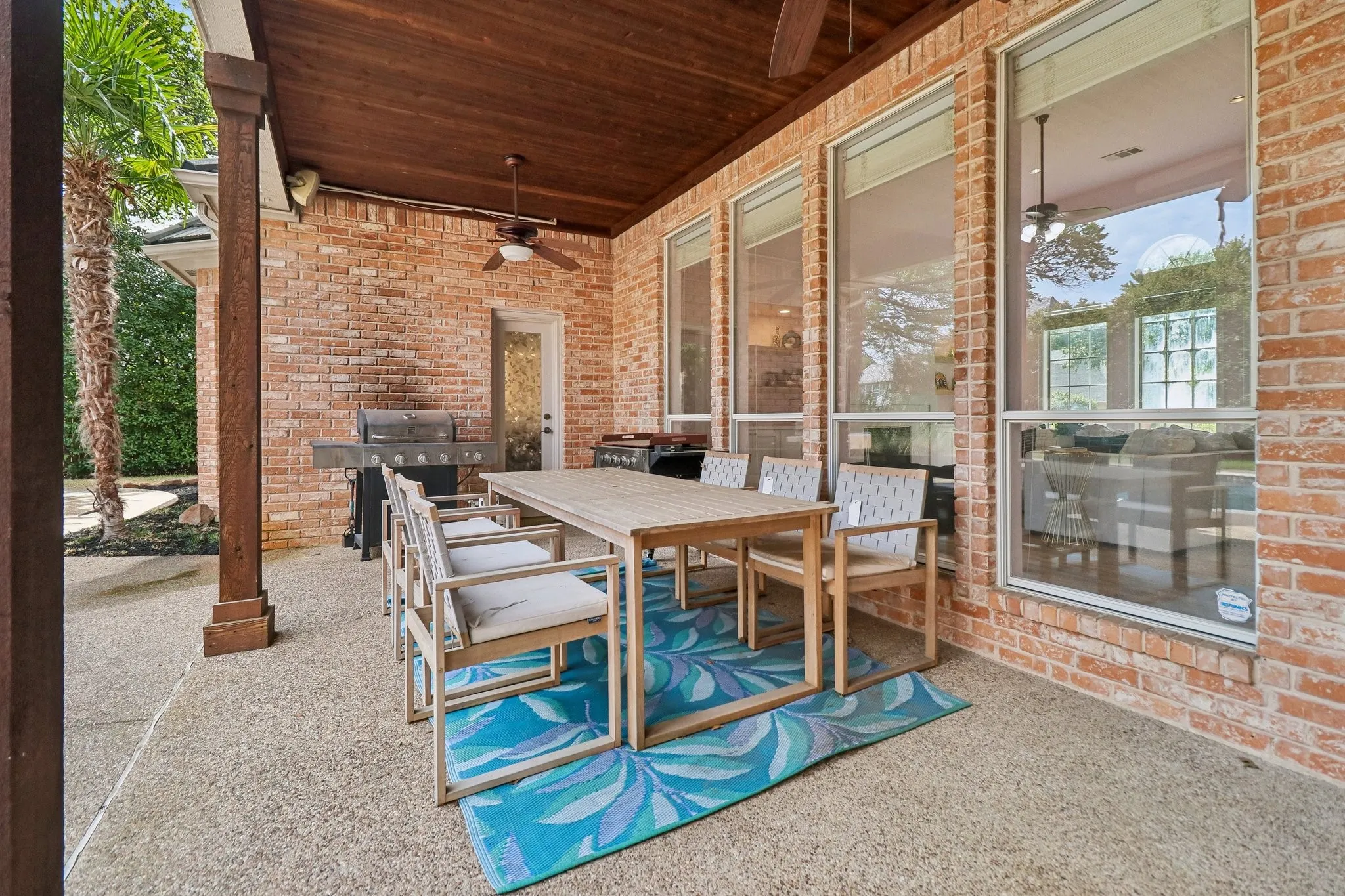 Covered patio featuring a wood-finish ceiling, exposed aggregate concrete flooring, and brick exterior walls