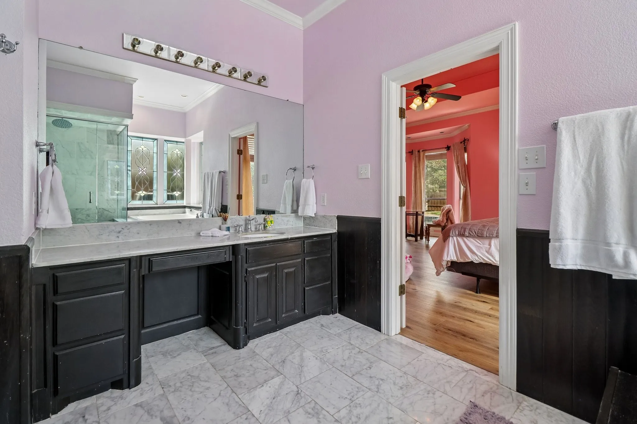 Bathroom with a dual vanity featuring dark cabinetry, a built-in vanity area, and a large mirror