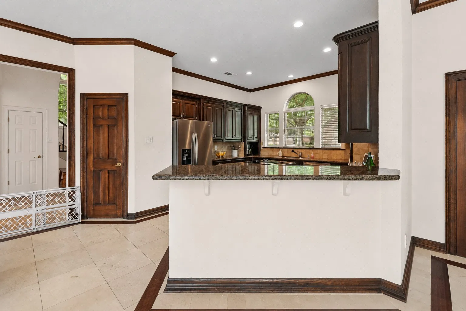 Kitchen featuring dark wood cabinetry, stainless steel appliances, a counter-height breakfast bar, and recessed lighting