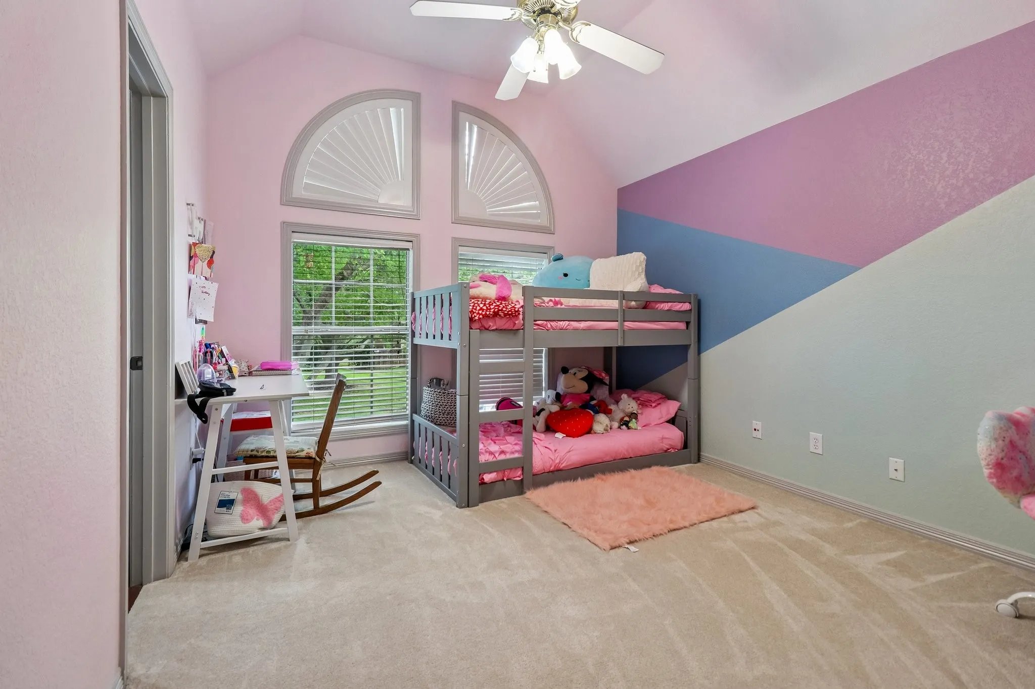 Vaulted ceiling with a ceiling fan, arched transom windows, and carpet flooring