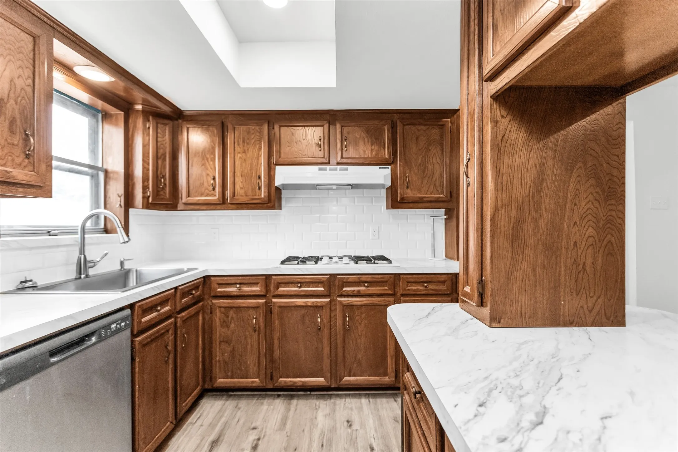U-shaped kitchen featuring wood cabinetry, white countertops, subway tile backsplash, and a gas range