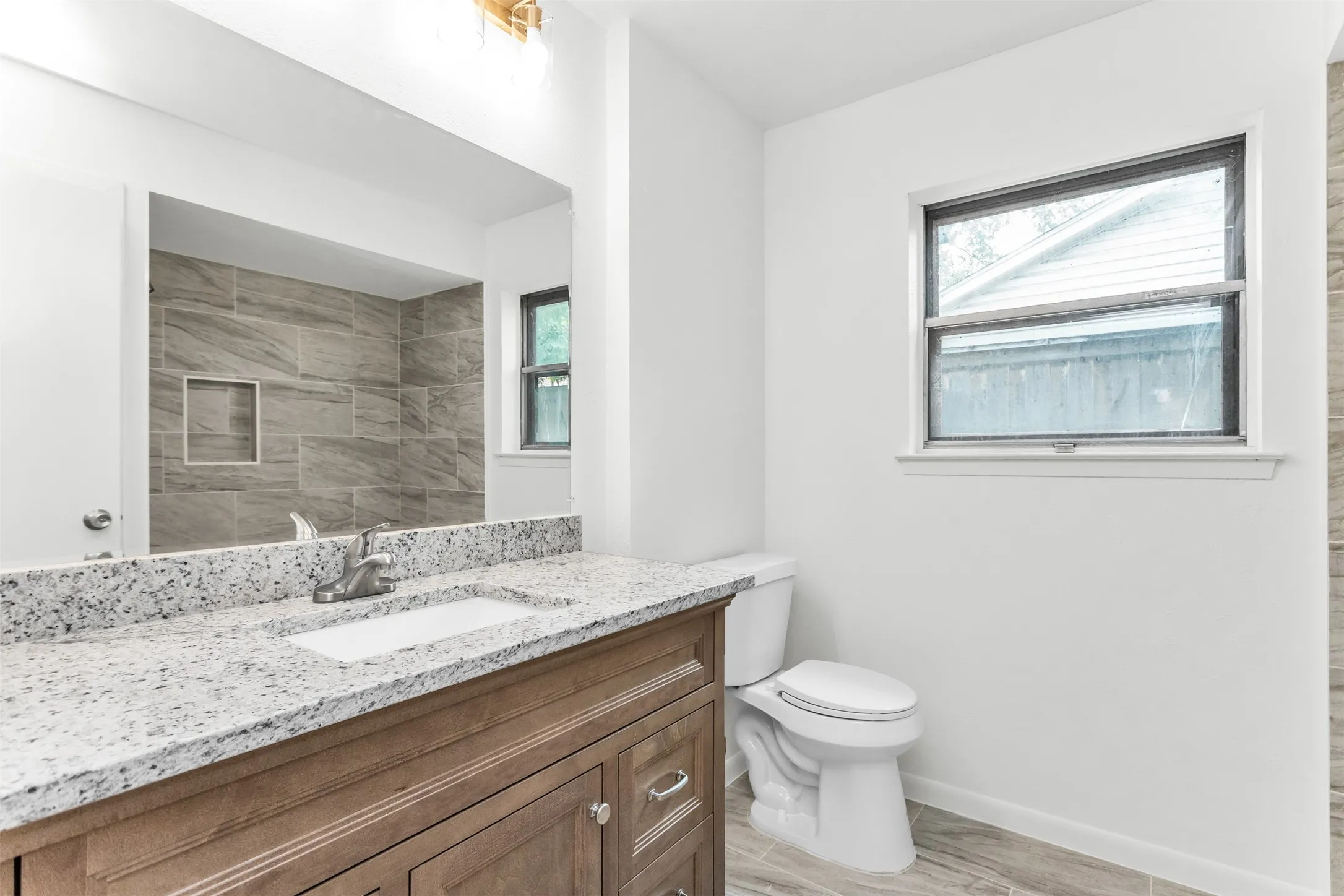 Wood-finish vanity with an integrated sink and granite-style countertop