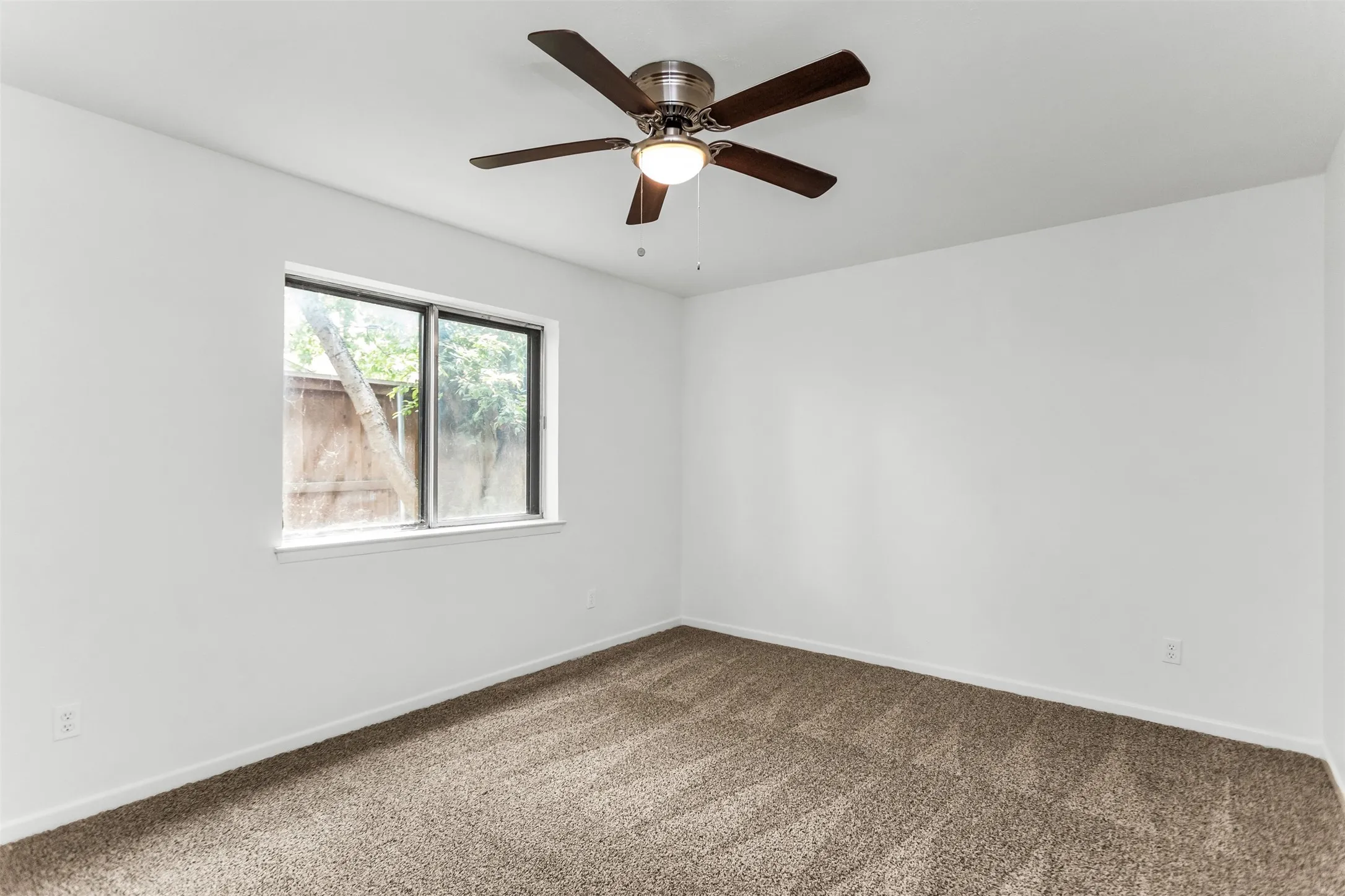 Neutral white wall paint, brown carpet flooring, and a ceiling fan with light fixture