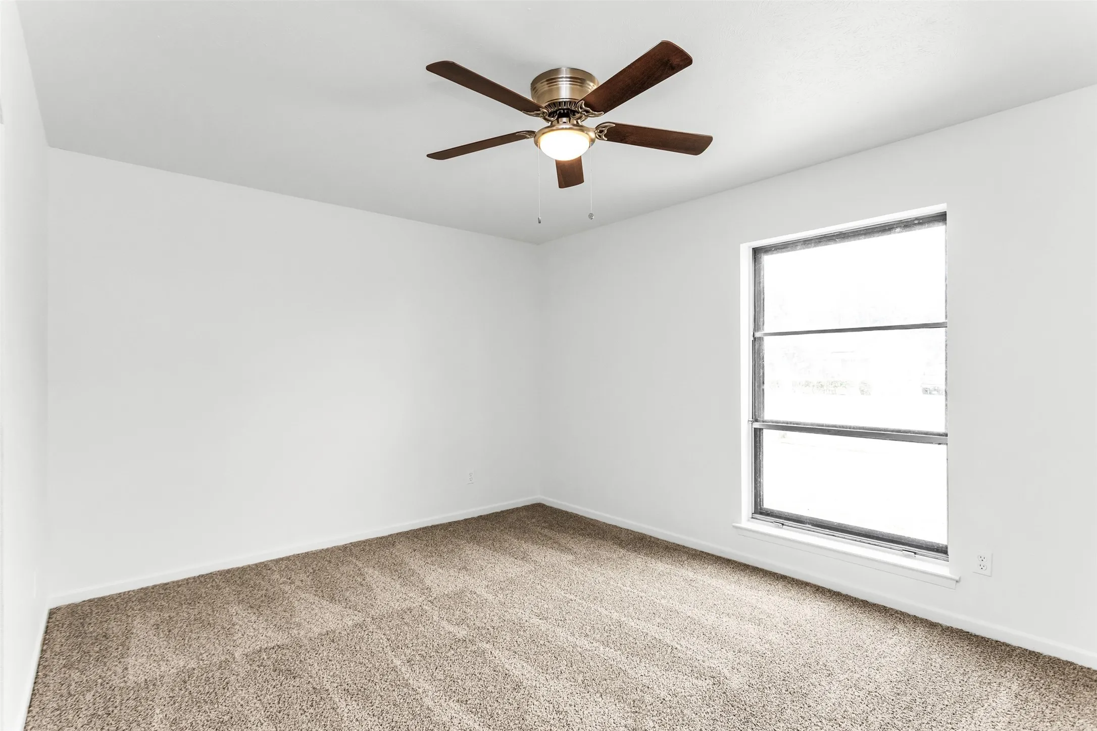 Neutral wall colors, carpeted flooring, and a ceiling fan with integrated lighting
