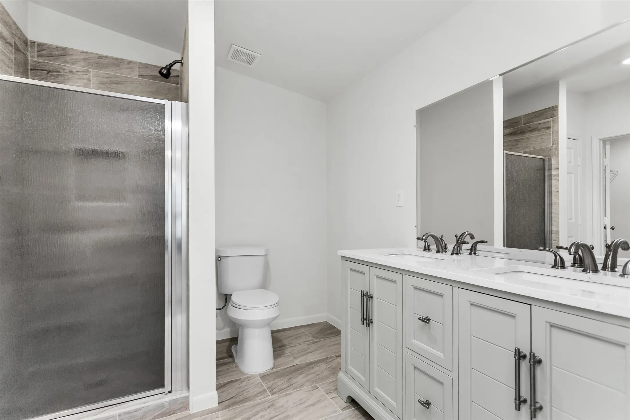 Dual vanity with white countertop, chrome hardware, and wood-finish flooring