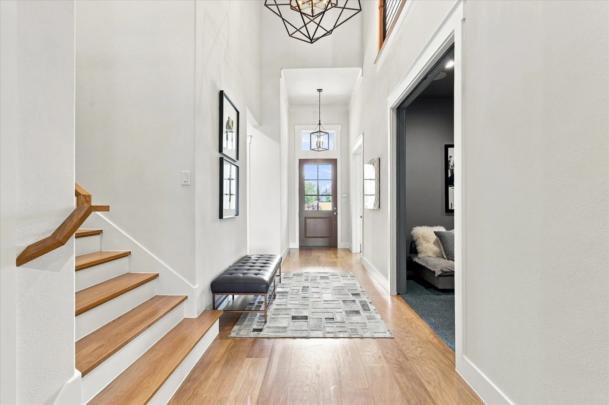 Two-story foyer with hardwood flooring, a contrasting wood staircase, and a wood-paneled door