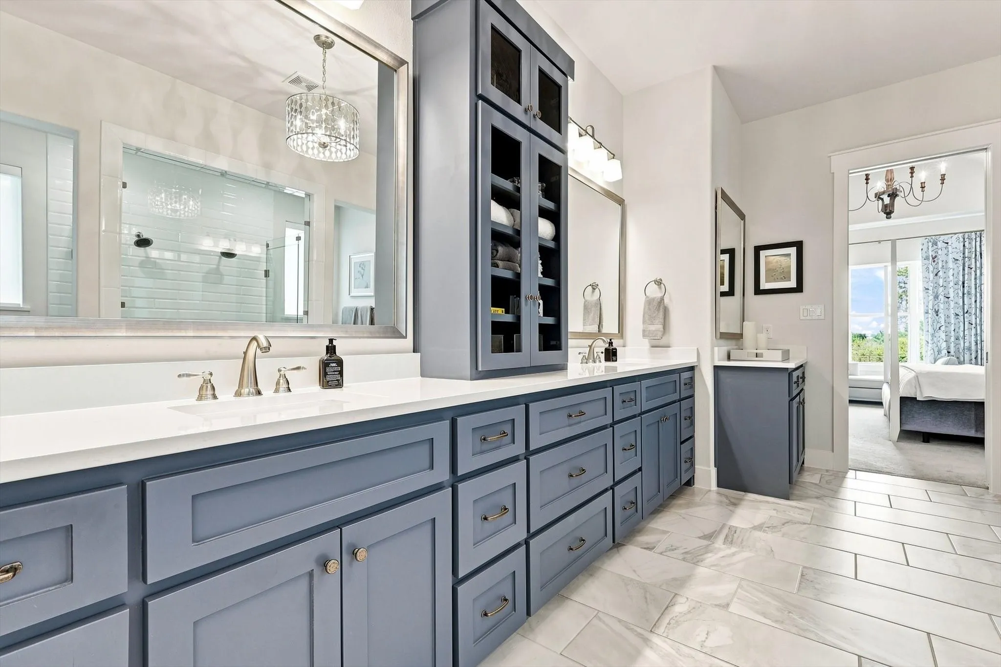 Double vanity with white countertops, undermount sinks, brushed nickel faucets, and extensive blue cabinetry with coordinating hardware