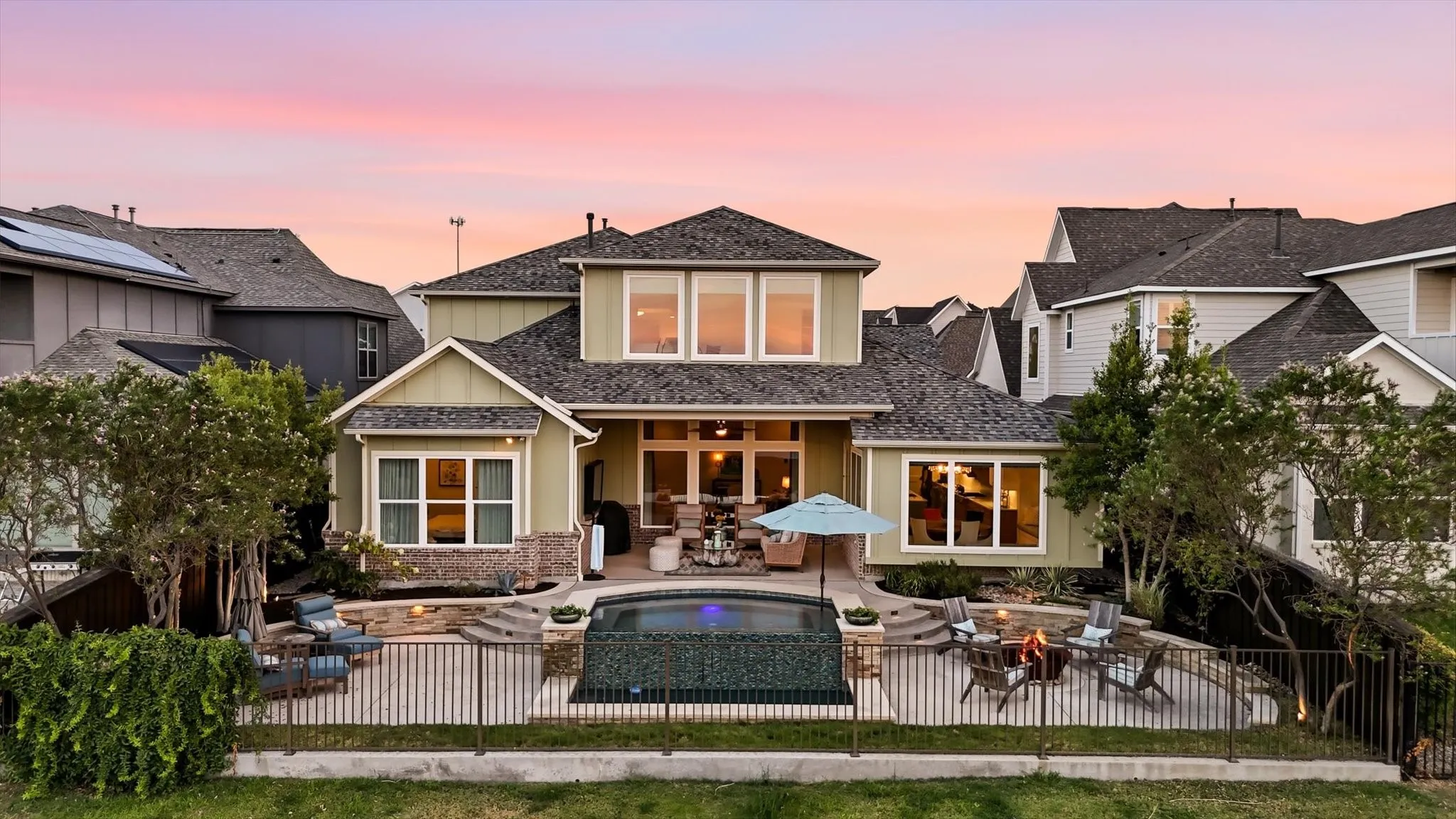 Two-story residence with a multi-level patio, infinity-edge pool, and a fenced yard
