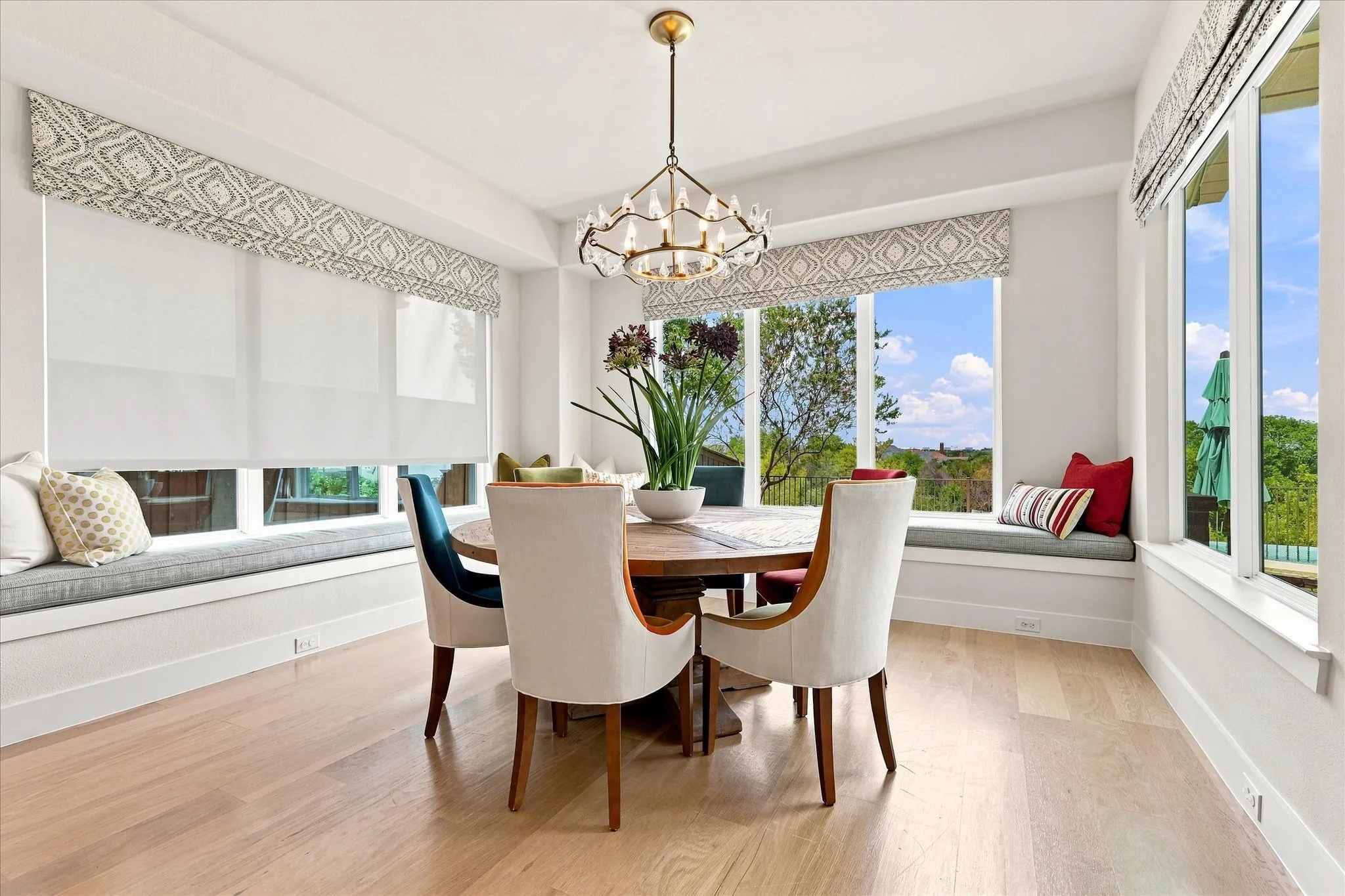 Light wood-finish flooring, built-in window seating, multiple windows, and a decorative chandelier