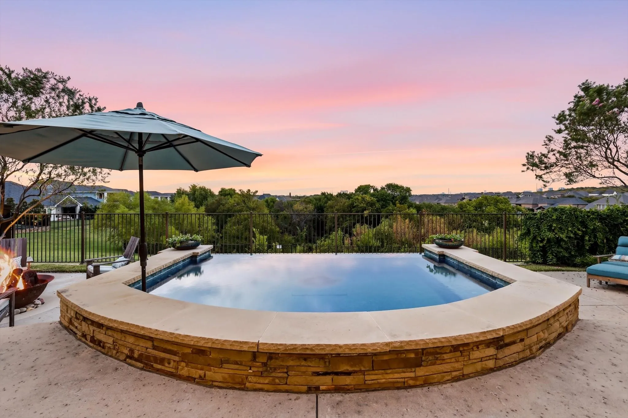 Infinity-edge pool with stone veneer surround and integrated planters