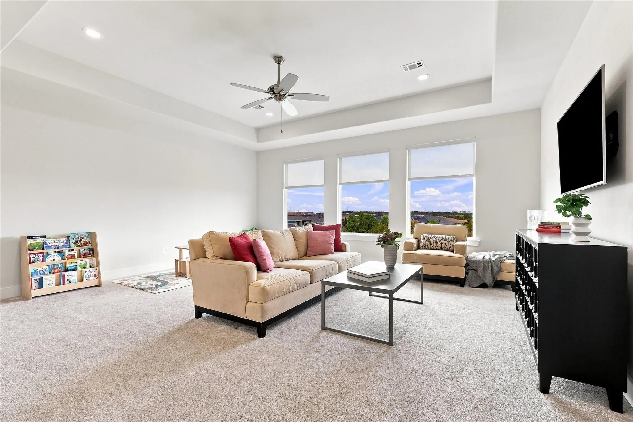 Tray ceiling with recessed lighting, ceiling fan, and light-colored carpet