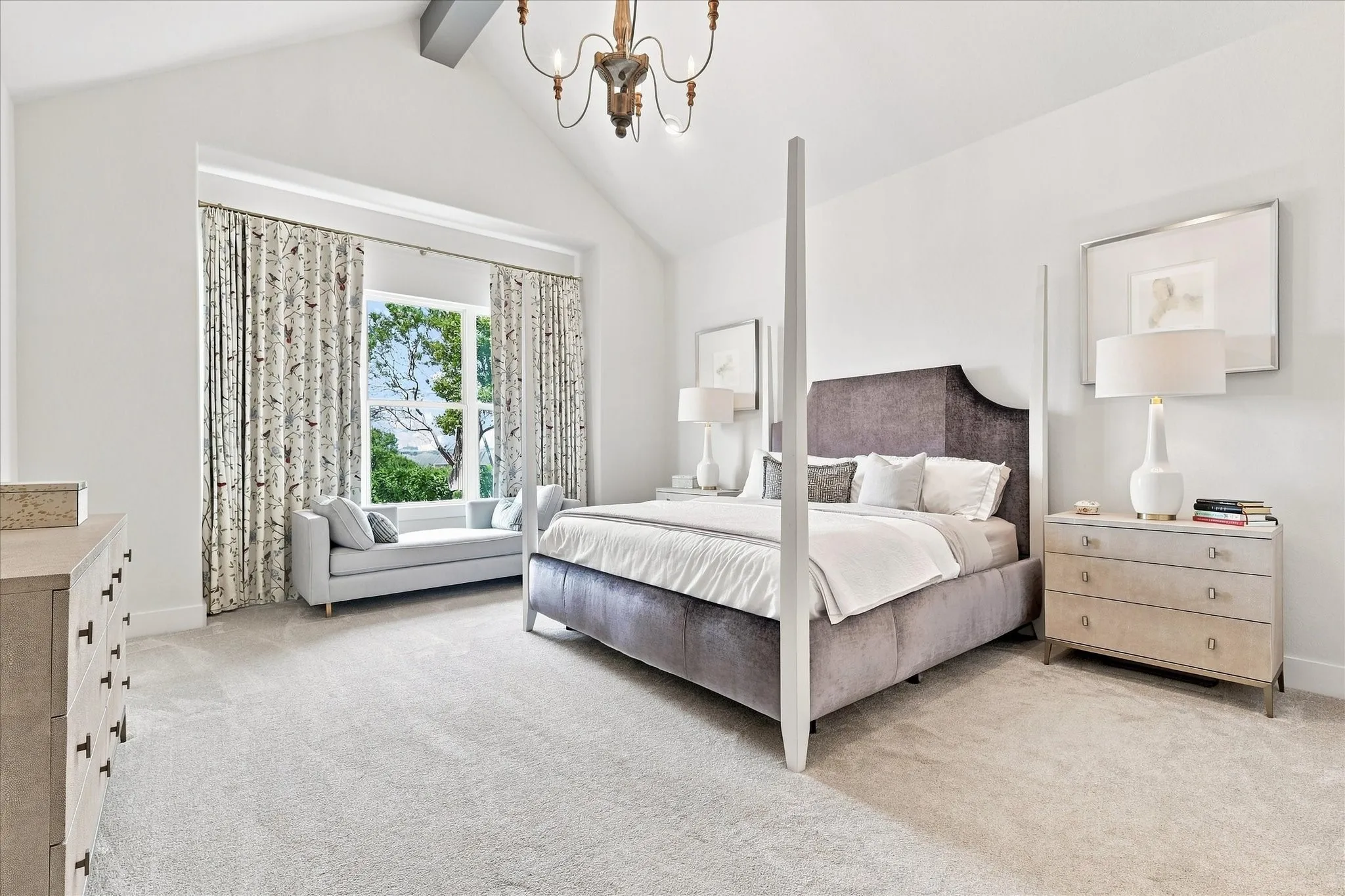 Vaulted ceiling with exposed beam, window seat with built-in storage, and chandelier